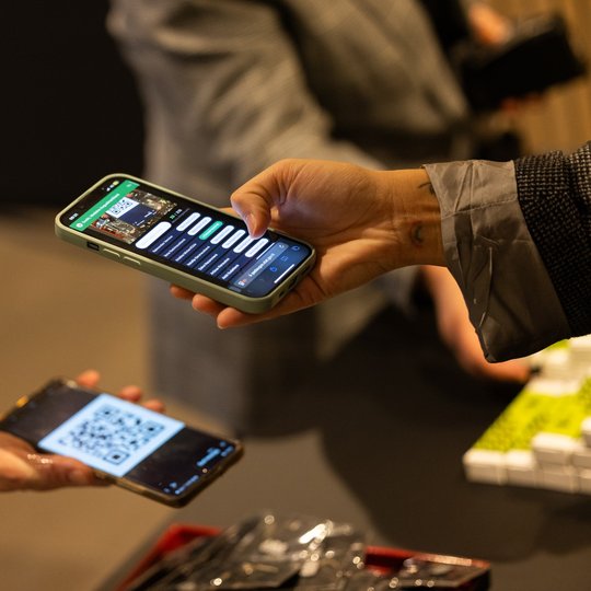Žmogus skenuoja QR kodą iš kito telefono